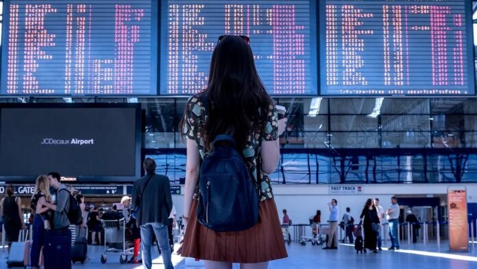 Chica en un aeropuerto con la maleta y los billetes de avión