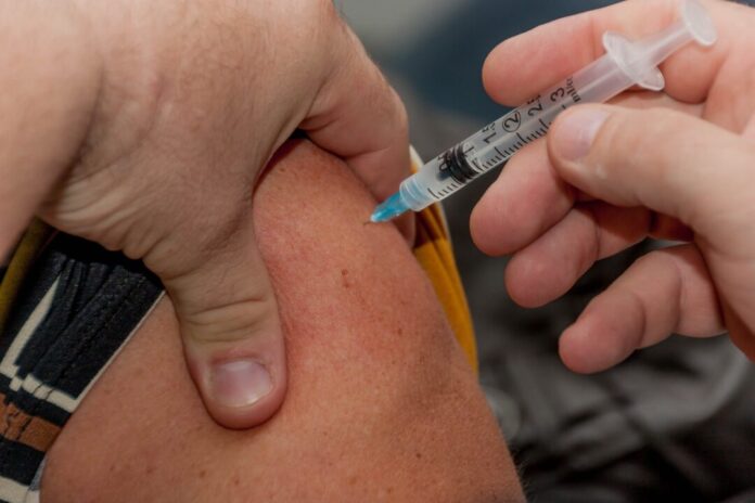 Sanitario administrando una dosis de la vacuna